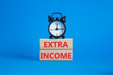 Extra Income symbol. Concept words Extra Income on wooden blocks. Beautiful blue background with alarm clock. Business and Extra Income concept. Copy space.の写真素材
