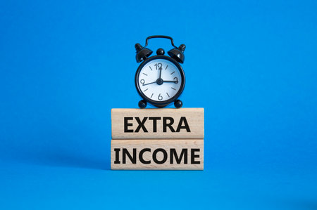 Extra Income symbol. Concept words Extra Income on wooden blocks. Beautiful blue background with alarm clock. Business and Extra Income concept. Copy space.の写真素材