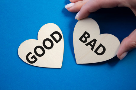Good or Bad symbol. Concept word Good or Bad on wooden hearts. Businessman hand. Beautiful blue...