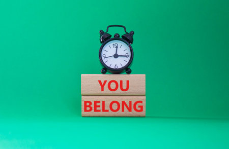 You belong symbol. Concept words You belong on wooden blocks. Beautiful green background with alarm clock. Business and You belong concept. Copy space.の写真素材
