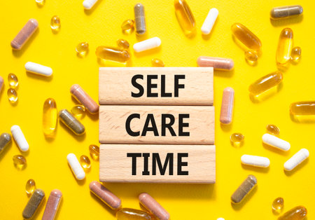 Self-care Time symbol. Concept words Self-care Time on wooden blocks. Beautiful yellow background with pills. Healthcare and Self-care Time concept. Copy space.の写真素材