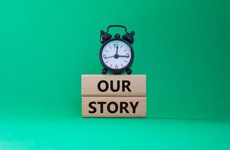 Our story symbol. Wooden blocks with words Our story Beautiful green background with alarm clock....
