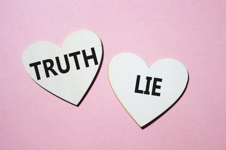 Truth or Lie symbol. Concept word Truth or Lie on wooden hearts. Beautiful pink background. Business and Truth or Lie concept. Copy spaceの写真素材