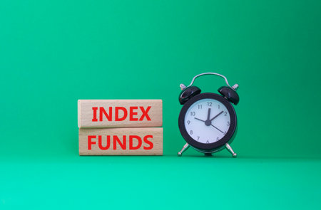 Index Funds symbol. Concept words Index Funds on wooden blocks. Beautiful green background with alarm clock. Business and Index Funds concept. Copy space.の写真素材