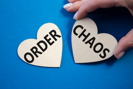 Chaos or Order symbol. Concept word Chaos or Order on wooden hearts. Businessman hand. Beautiful blue background. Business and Chaos or Order concept. Copy spaceの写真素材