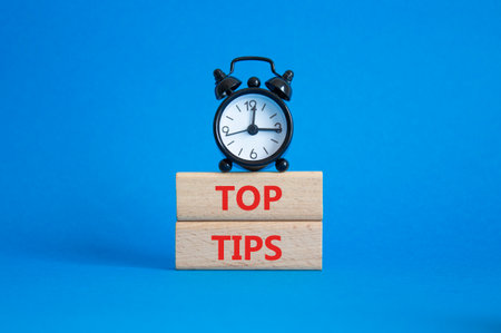 Top Tips symbol. Concept words Top Tips on wooden blocks. Beautiful blue background with alarm clock. Business and Top Tips concept. Copy space.の写真素材