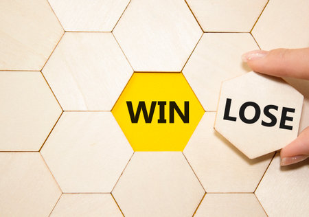 Win or Lose symbol. Concept word Win or Lose on wooden comb puzzle. Businessman hand. Beautiful yellow background. Business and Win or Lose concept. Copy spaceの写真素材