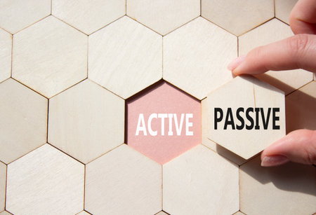 Active or Passive symbol. Concept word Active or Passive on wooden comb puzzle. Businessman hand. Beautiful pink background. Business and Active or Passive concept. Copy spaceの写真素材