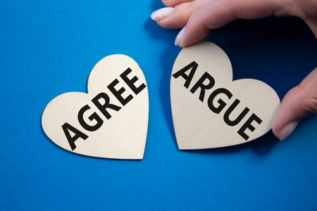 Agree or Argue symbol. Concept word Agree or Argue on wooden hearts. Businessman hand. Beautiful blue background. Business and Agree or Argue concept. Copy spaceの写真素材