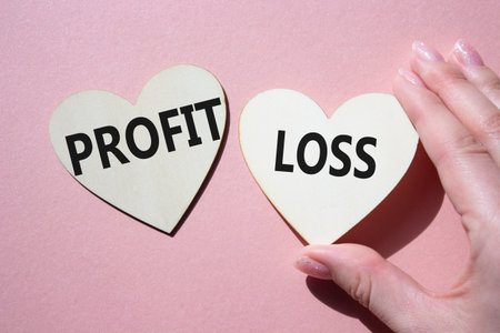 Profit or Loss symbol. Concept word Profit or Loss on wooden hearts. Businessman hand. Beautiful pink background. Business and Profit or Loss concept. Copy spaceの写真素材