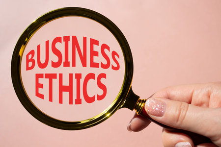 Business ethics symbol. Concept word Business ethics on magnifying glass. Businessman hand. Beautiful pink background. Business and Business ethics concept. Copy spaceの写真素材