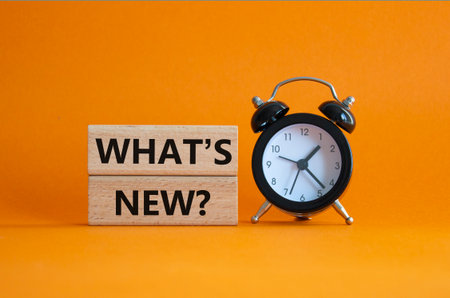 What is new symbol. Concept word What is new on wooden blocks. Beautiful orange background with alarm clock. Business and What is new concept. Copy spaceの写真素材