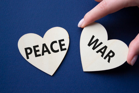 War or Peace symbol. Concept word War or Peace on wooden hearts. Businessman hand. Beautiful deep blue background. Business and War or Peace concept. Copy spaceの写真素材
