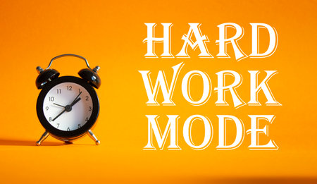 Hard Work Mode symbol. Concept word Hard Work Mode on Beautiful orange background with alarm clock. Business and Hard Work Mode concept. Copy spaceの写真素材