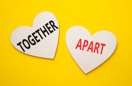 Together or Apart symbol. Concept word Together or Apart on wooden hearts. Beautiful yellow background. Business and Together or Apart concept. Copy spaceの写真素材