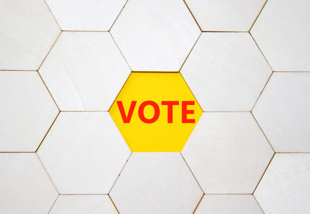 Vote symbol. Concept word Vote on wooden comb puzzle. Beautiful yellow background. Business and Vote...