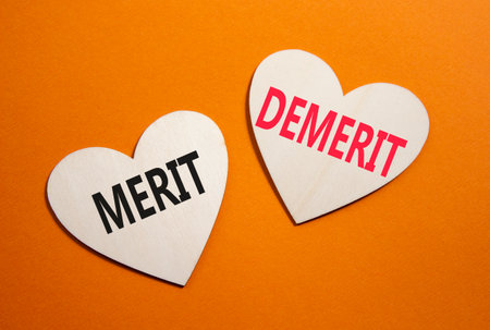 Merit or Demerit symbol. Concept word Merit or Demerit on wooden hearts. Beautiful orange background. Business and Merit or Demerit concept. Copy spaceの写真素材