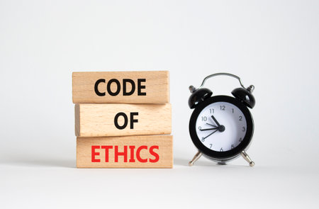 Code of ethics symbol. Concept words Code of ethics on wooden blocks with alarm clock. Beautiful white background. Business and Code of ethics concept. Copy space.の写真素材