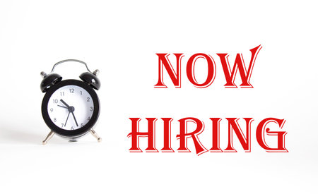 Now Hiring symbol. Concept word Now Hiring on Beautiful white background with alarm clock. Business...
