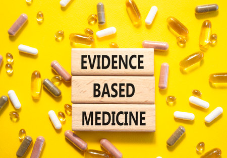 Evidence Based Medicine symbol. Concept word Evidence Based Medicine on wooden blocks. Beautiful yellow background with pills. Medicine and Evidence Based Medicine concept. Copy spaceの写真素材