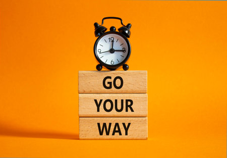 Go Your Way symbol. Wooden blocks with words Go Your Way. Beautiful orange background with alarm clock. Business and Go Your Way concept. Copy space.の写真素材