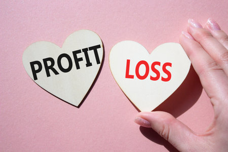Profit or Loss symbol. Concept word Profit or Loss on wooden hearts. Businessman hand. Beautiful pink background. Business and Profit or Loss concept. Copy spaceの写真素材
