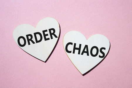 Chaos or Order symbol. Concept word Chaos or Order on wooden hearts. Beautiful pink background....