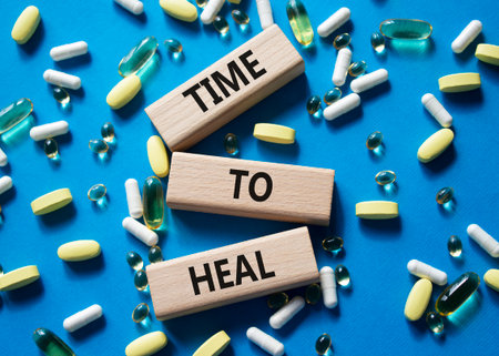 Medicine symbol. Concept words Time to Heal on wooden blocks. Beautiful blue background with pills. Medicine concept and Time to Heal. Copy spaceの写真素材