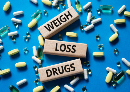 Medicine symbol. Concept words Weight Loss Drugs on wooden blocks. Beautiful blue background with pills. Medicine concept and Weight Loss Drugs. Copy spaceの写真素材