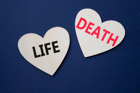 Life or Death symbol. Concept word Life or Death on wooden hearts. Beautiful deep blue background. Business and Life or Death concept. Copy spaceの写真素材