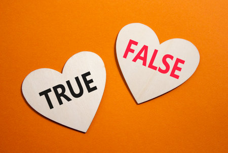 True or False symbol. Concept word True or False on wooden hearts. Beautiful orange background. Business and True or False concept. Copy spaceの写真素材