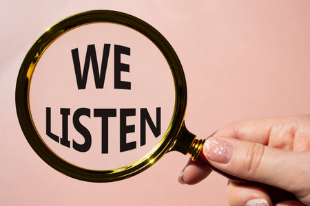 We listen symbol. Concept words We listen on magnifying glass. Beautiful pink background. Businessman hand. Business and We listen concept. Copy space.の写真素材