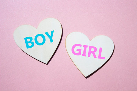 Boy or Girl symbol. Concept word Boy or Girl on wooden hearts. Beautiful pink background. Gender and Boy or Girl concept. Copy spaceの写真素材