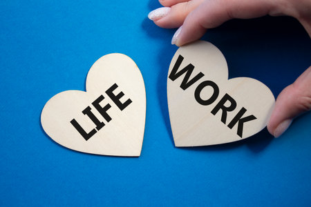 Life or Work symbol. Concept word Life or Work on wooden hearts. Businessman hand. Beautiful blue background. Business and Life or Work concept. Copy spaceの写真素材