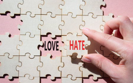 Love vs Hate symbol. Concept word Love vs Hate on wooden puzzle. Businessman hand. Beautiful pink background. Business and Love vs Hate concept. Copy spaceの写真素材
