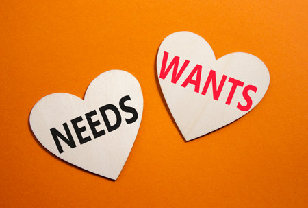 Wants and Needs symbol. Concept word Wants and Needs on wooden hearts. Beautiful orange background. Business and Wants and Needs concept. Copy spaceの写真素材
