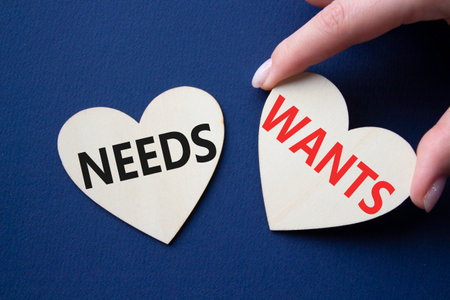Wants and Needs symbol. Concept word Wants and Needs on wooden hearts. Businessman hand. Beautiful deep blue background. Business and Wants and Needs concept. Copy spaceの写真素材