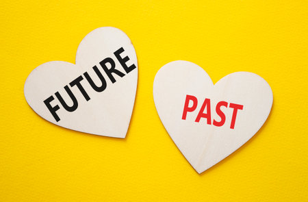 Future or Past symbol. Concept word Future or Past on wooden hearts. Beautiful yellow background. Business and Future or Past concept. Copy spaceの写真素材
