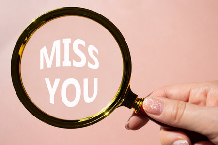 Miss you symbol. Magnifying Glass with Concept word Miss you. Beautiful pink background. Businessman hand. Miss you concept. Copy spaceの写真素材