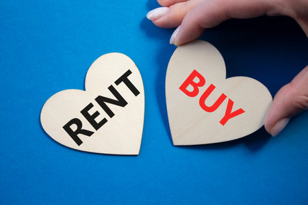 Rent or Buy symbol. Concept word Rent or Buy on wooden hearts. Businessman hand. Beautiful blue background. Business and Rent or Buy concept. Copy spaceの写真素材