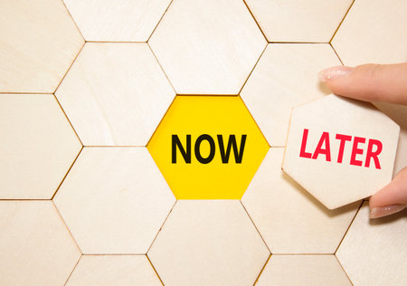 Now vs Later symbol. Concept word Now vs Later on wooden comb puzzle. Businessman hand. Beautiful yellow background. Business and Now vs Later concept. Copy spaceの写真素材
