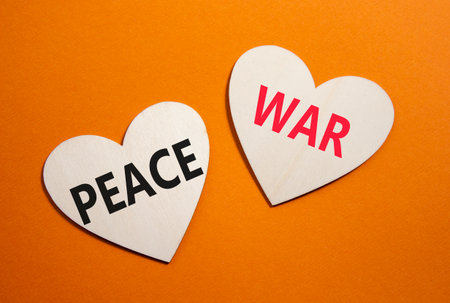 War or Peace symbol. Concept word War or Peace on wooden hearts. Beautiful orange background. Business and War or Peace concept. Copy spaceの写真素材