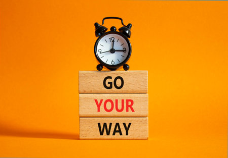 Go Your Way symbol. Wooden blocks with words Go Your Way. Beautiful orange background with alarm clock. Business and Go Your Way concept. Copy space.の写真素材