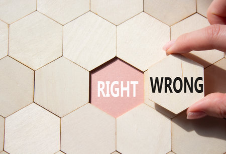 Right or Wrong symbol. Concept word Right or Wrong on wooden comb puzzle. Businessman hand. Beautiful pink background. Business and Right or Wrong concept. Copy spaceの写真素材