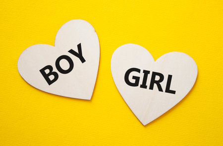 Boy or Girl symbol. Concept word Boy or Girl on wooden hearts. Beautiful yellow background. Gender and Boy or Girl concept. Copy spaceの写真素材