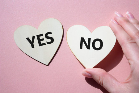 Yes or No symbol. Concept word Yes or No on wooden hearts. Businessman hand. Beautiful pink...