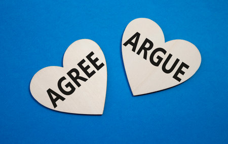 Agree or Argue symbol. Concept word Agree or Argue on wooden hearts. Beautiful blue background. Business and Agree or Argue concept. Copy spaceの写真素材