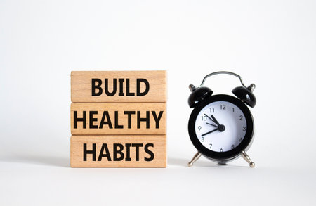 Healthy habits symbol. Concept word Build Healthy habits on wooden blocks with alarm clock. Beautiful white background. Healthy lifestyle and Healthy habits concept. Copy spaceの写真素材