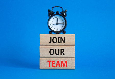 Join our team symbol. Wooden blocks with words Join our team. Beautiful blue background with alarm...