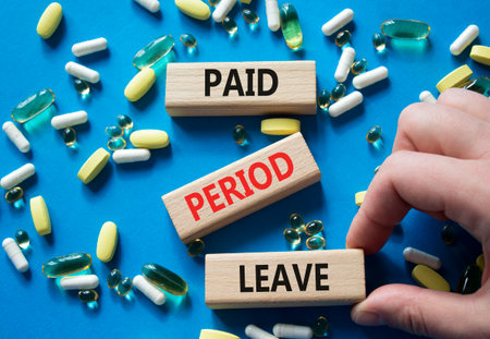 Paid Period Leave symbol. Concept words Paid Period Leave on wooden blocks. Beautiful blue background with pills. Doctor hand. Healthcare and Paid Period Leave concept. Copy space.の写真素材